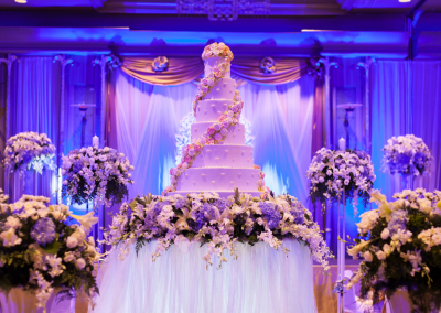 wedding cake at event venue purple and white flowers