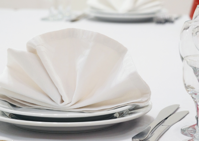 white plates with white napking fanned in the center of the plate